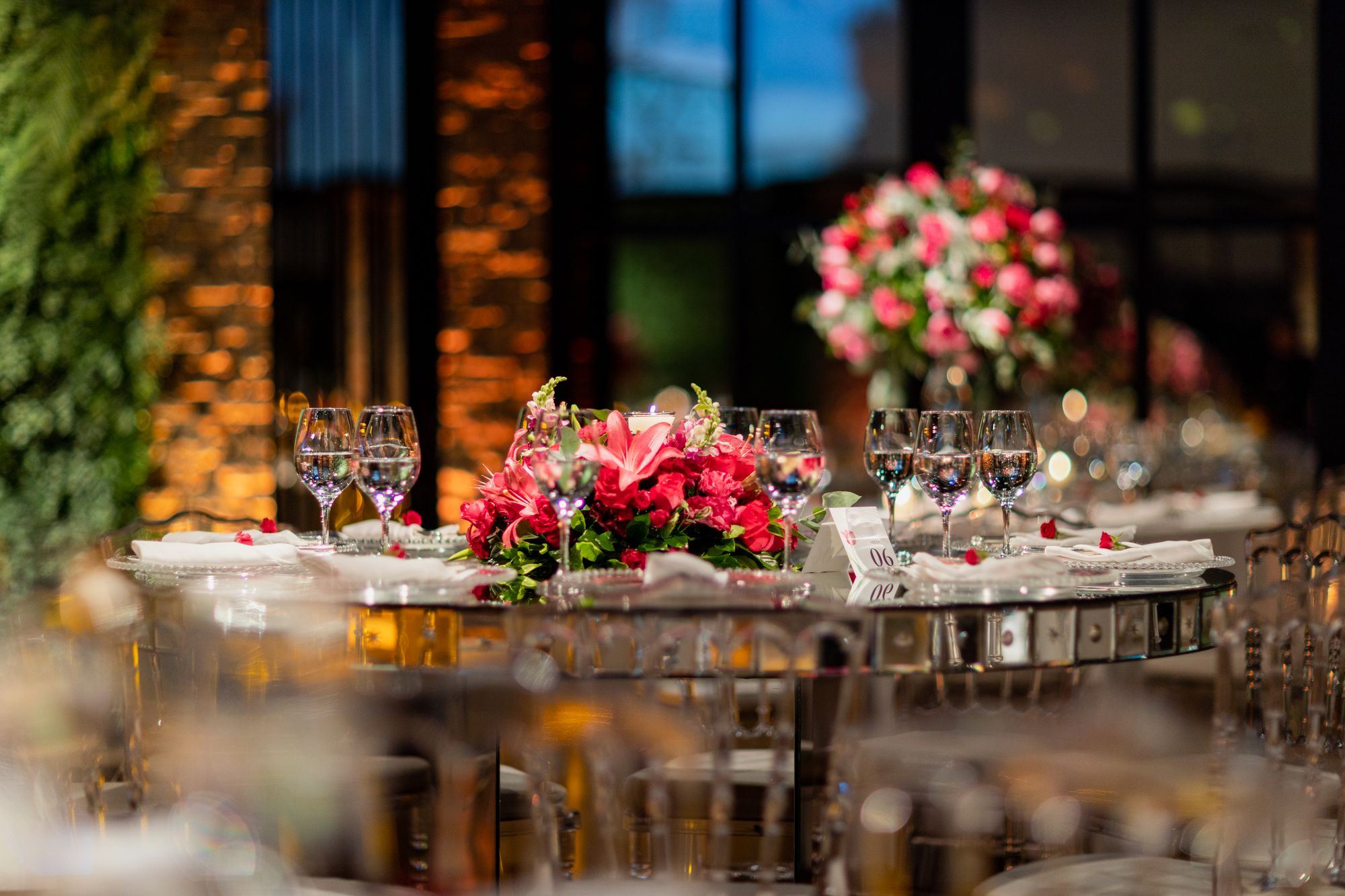 Mesa de banquete con centro de mesa de flores rojas y luz cálida en un salón de eventos